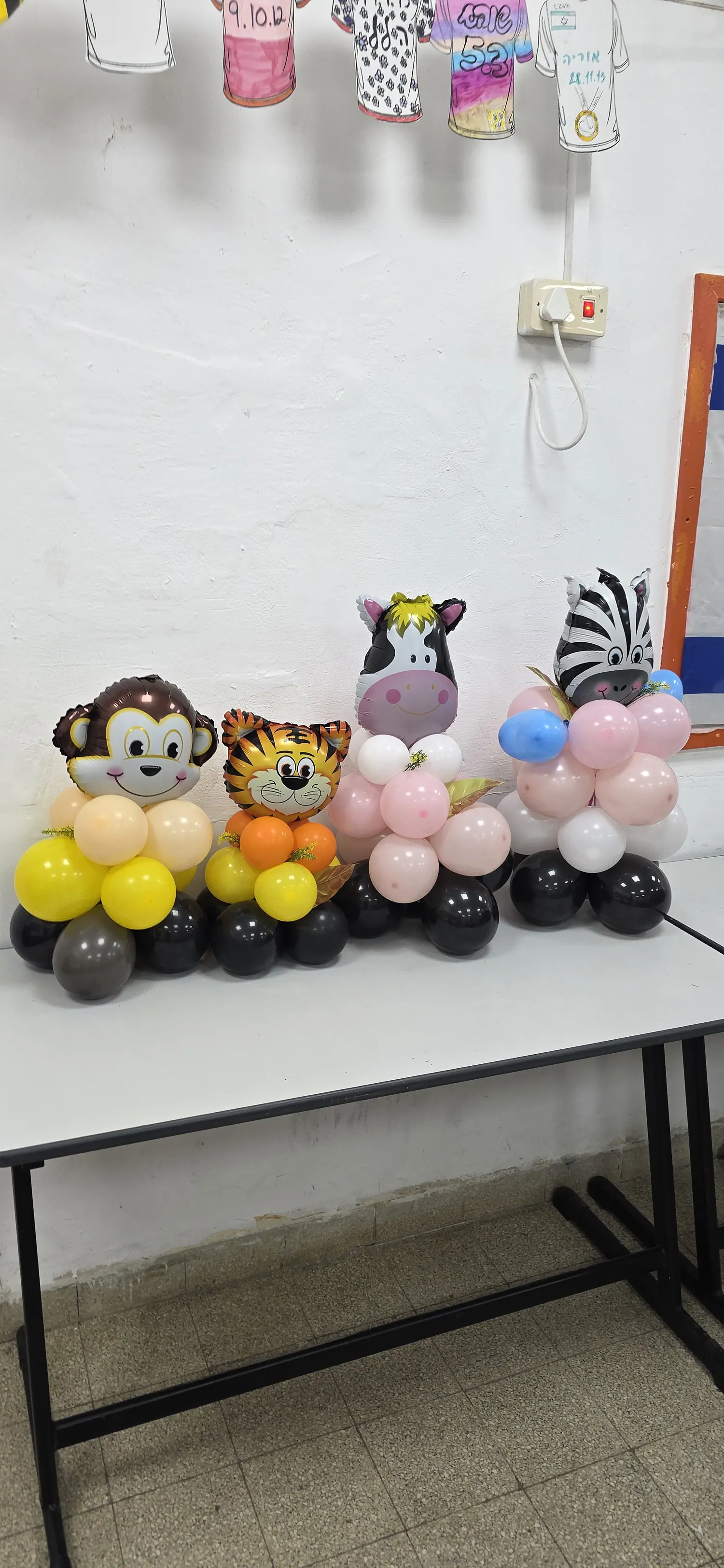 דמויות בלונים של קוף, טיגריס וזברה על שולחן הסדנה
