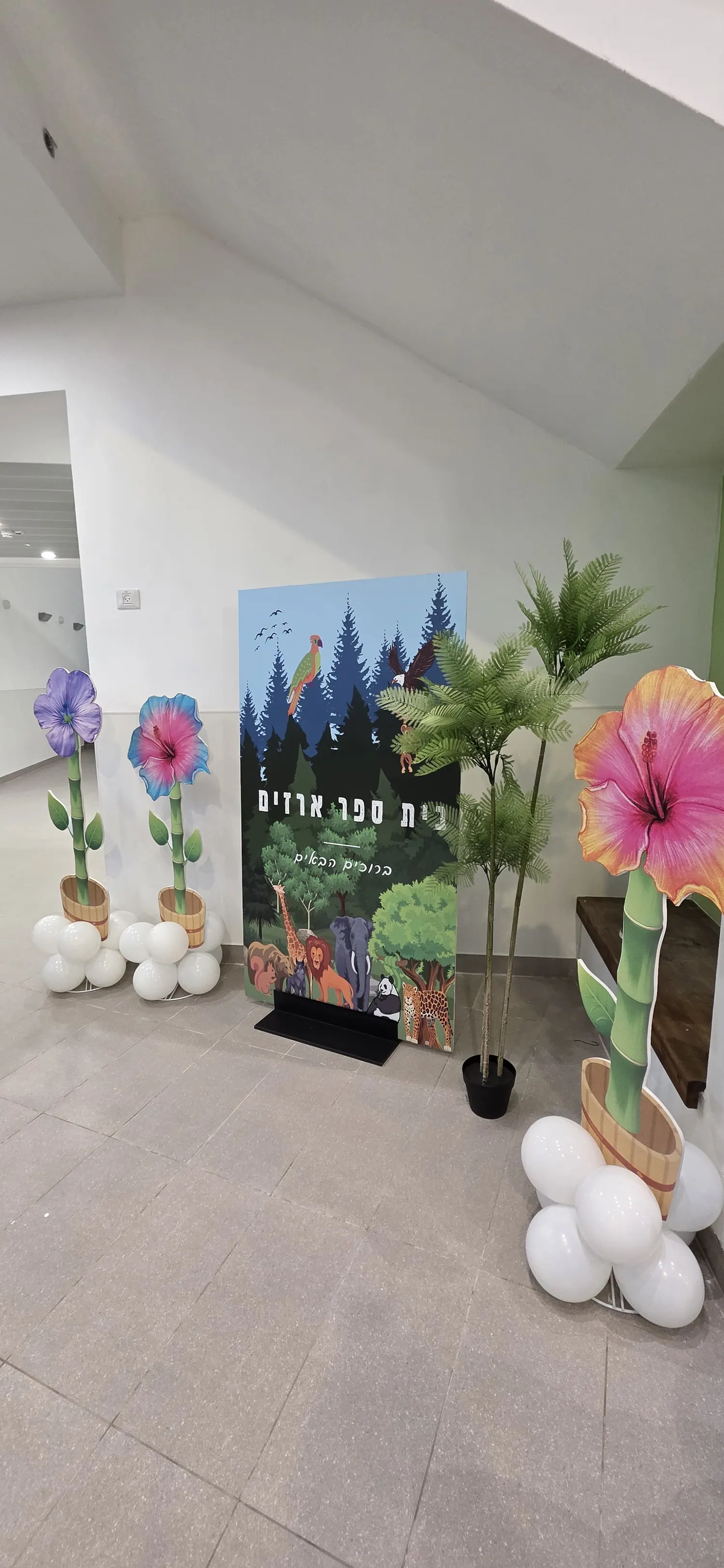 רקע פרחוני צבעוני עם עמודי בלונים בכניסה לאירוע
