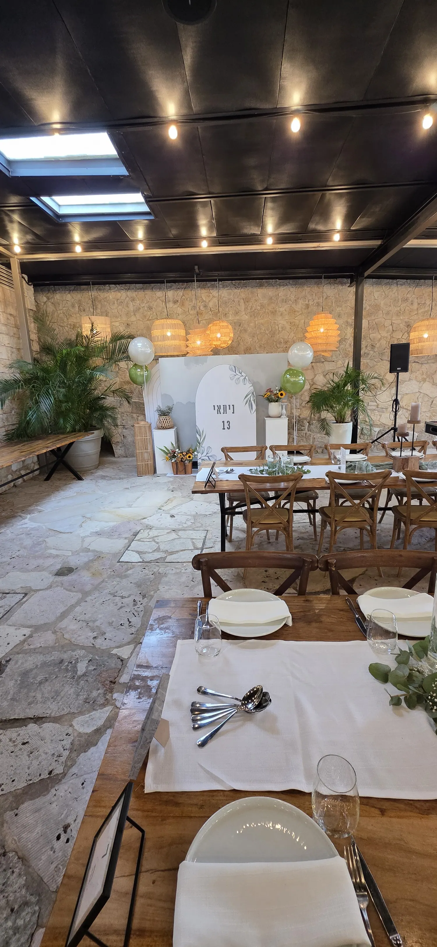 קשת לבנה גדולה עם פרחי חמניות בכניסה לאירוע חוץ