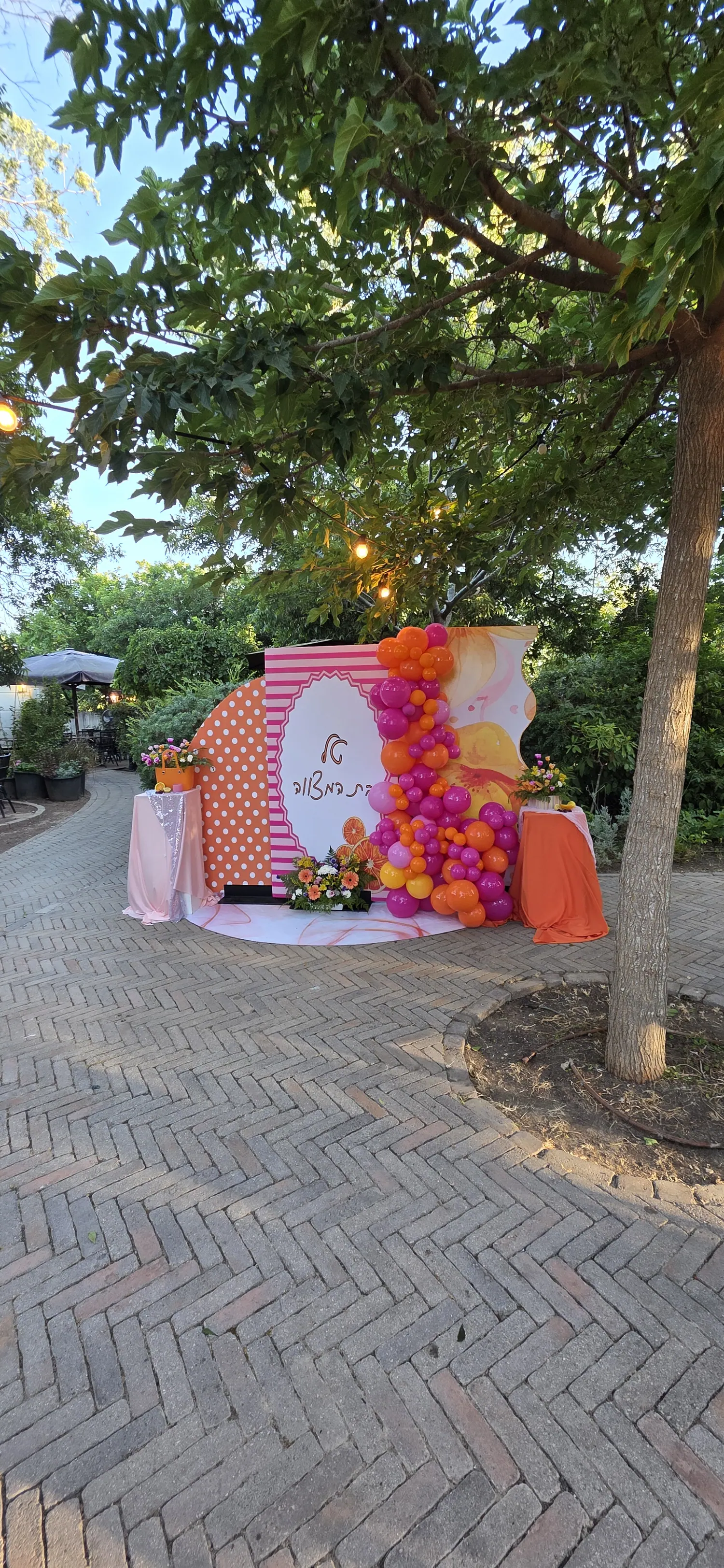 רקע פסים ורודים וכתומים עם קשת בלונים וזר פרחים