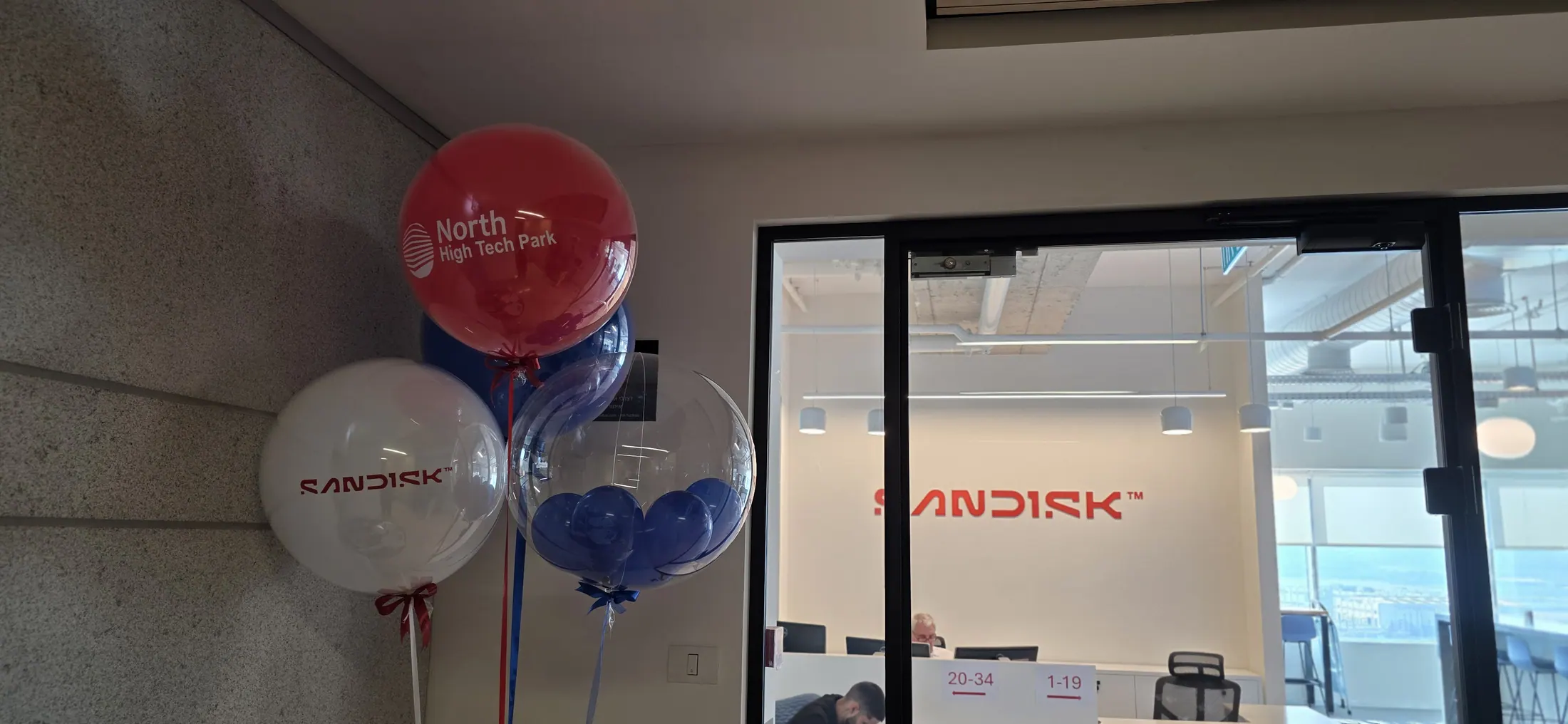 עמדת קבלה עם בלוני מתנה כחולים מול לובי משרד ממותג
