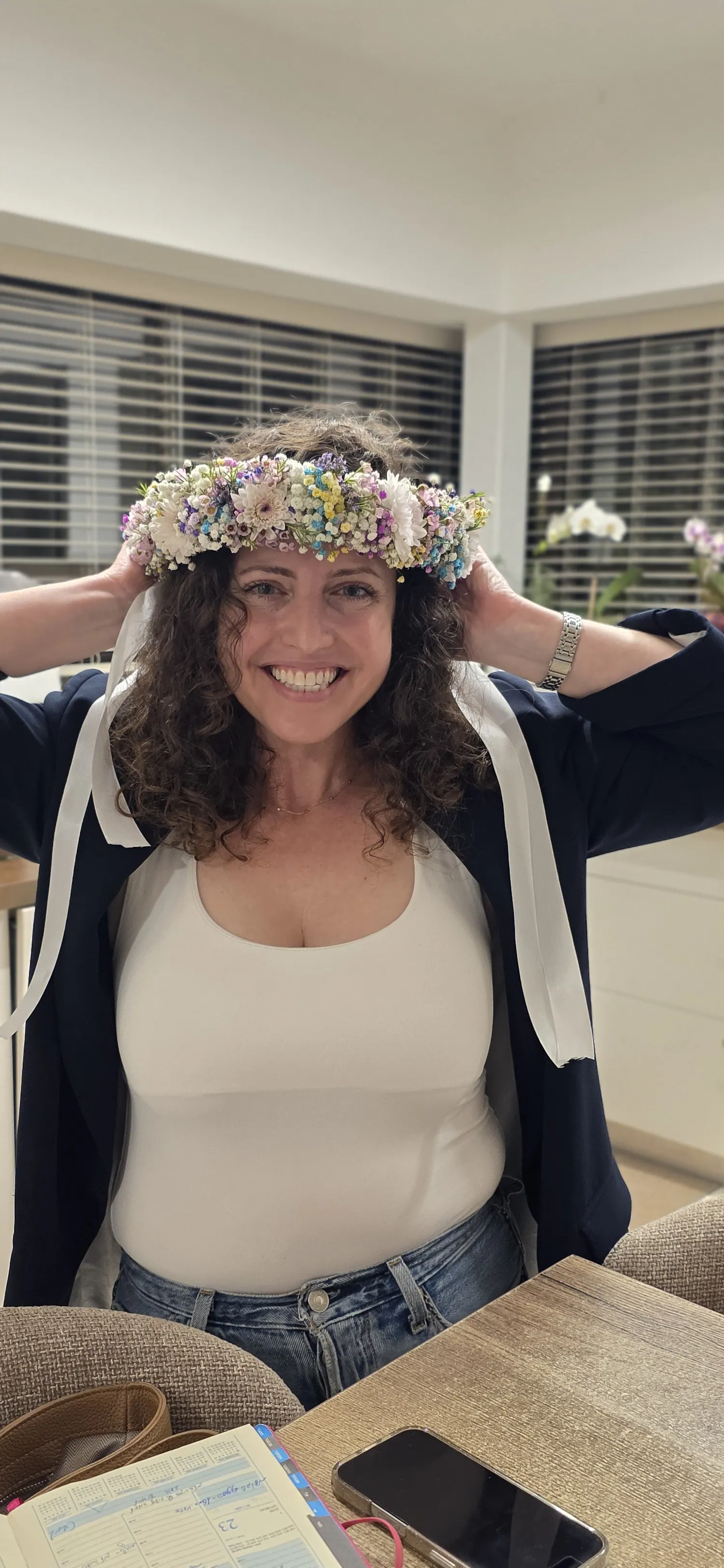 משתתפת מחייכת עונדת זר ראש פרחוני שיצרה בסדנה
