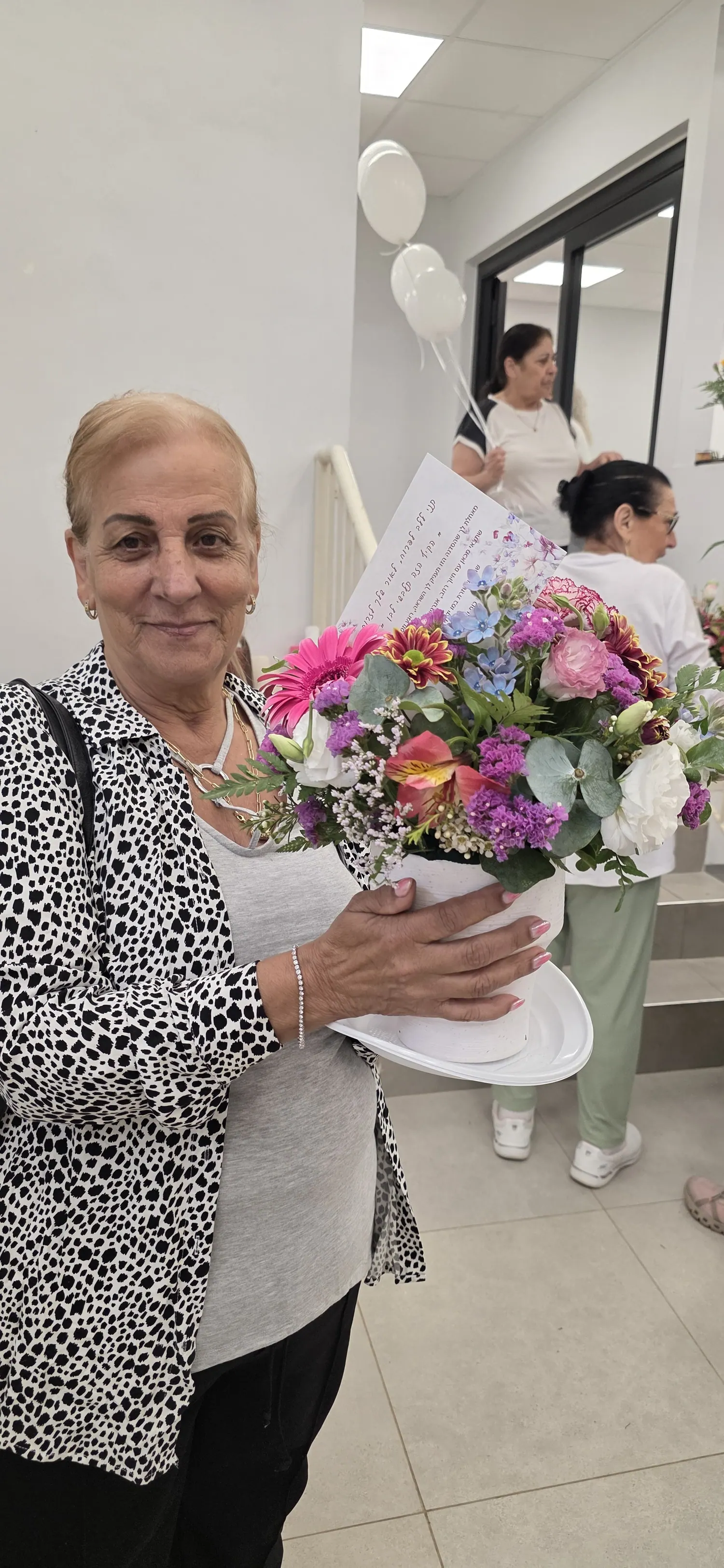 משתתפת מחזיקה זר פרחים צבעוני שיצרה