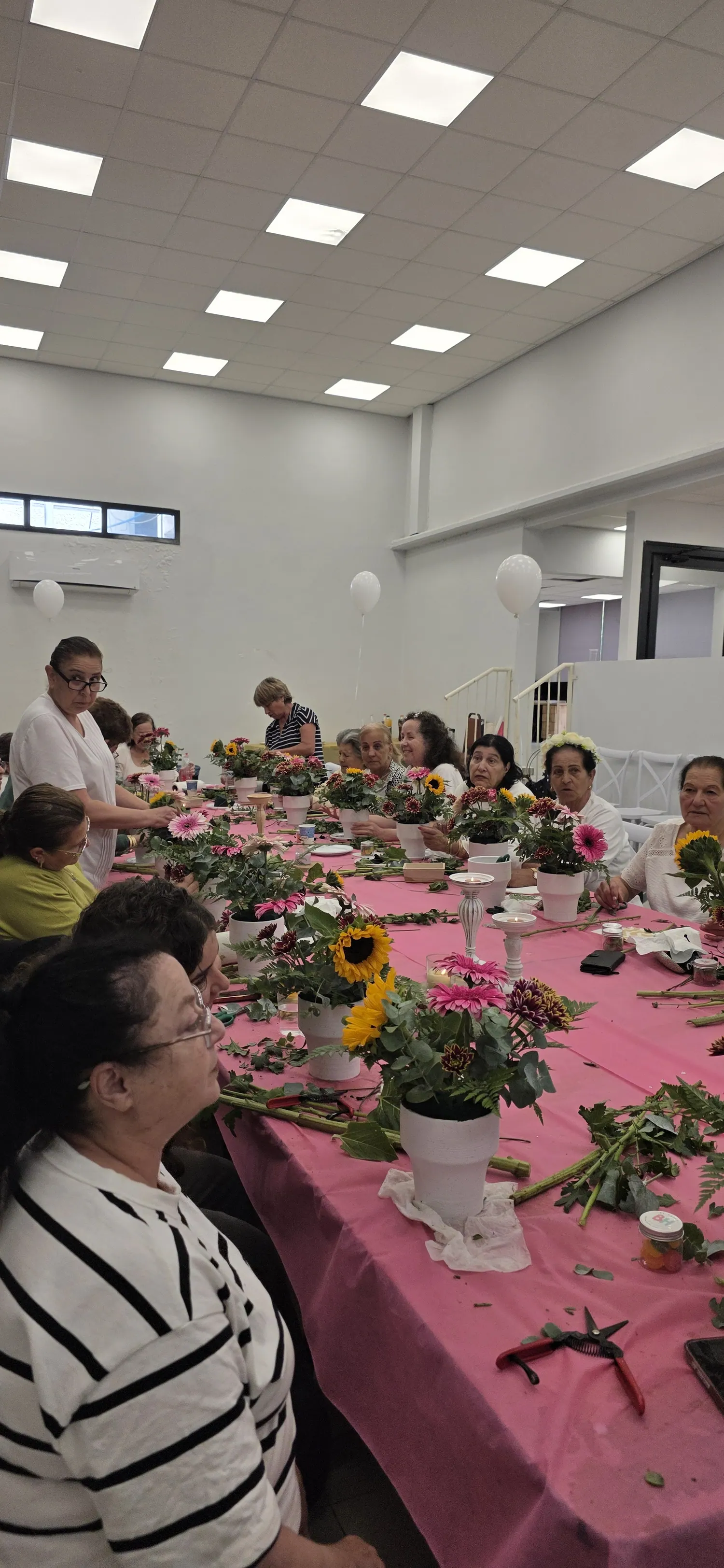 קבוצת משתתפות עובדת יחד בסדנת פרחים בחלל גדול