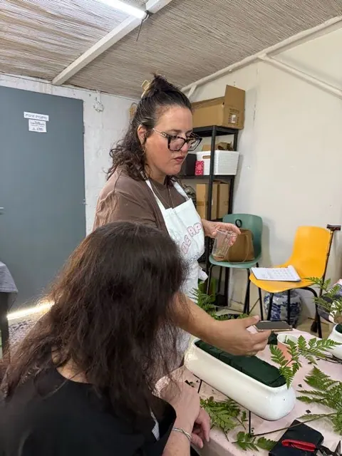 מדריכה מסבירה על שזירת פרחים בסדנה