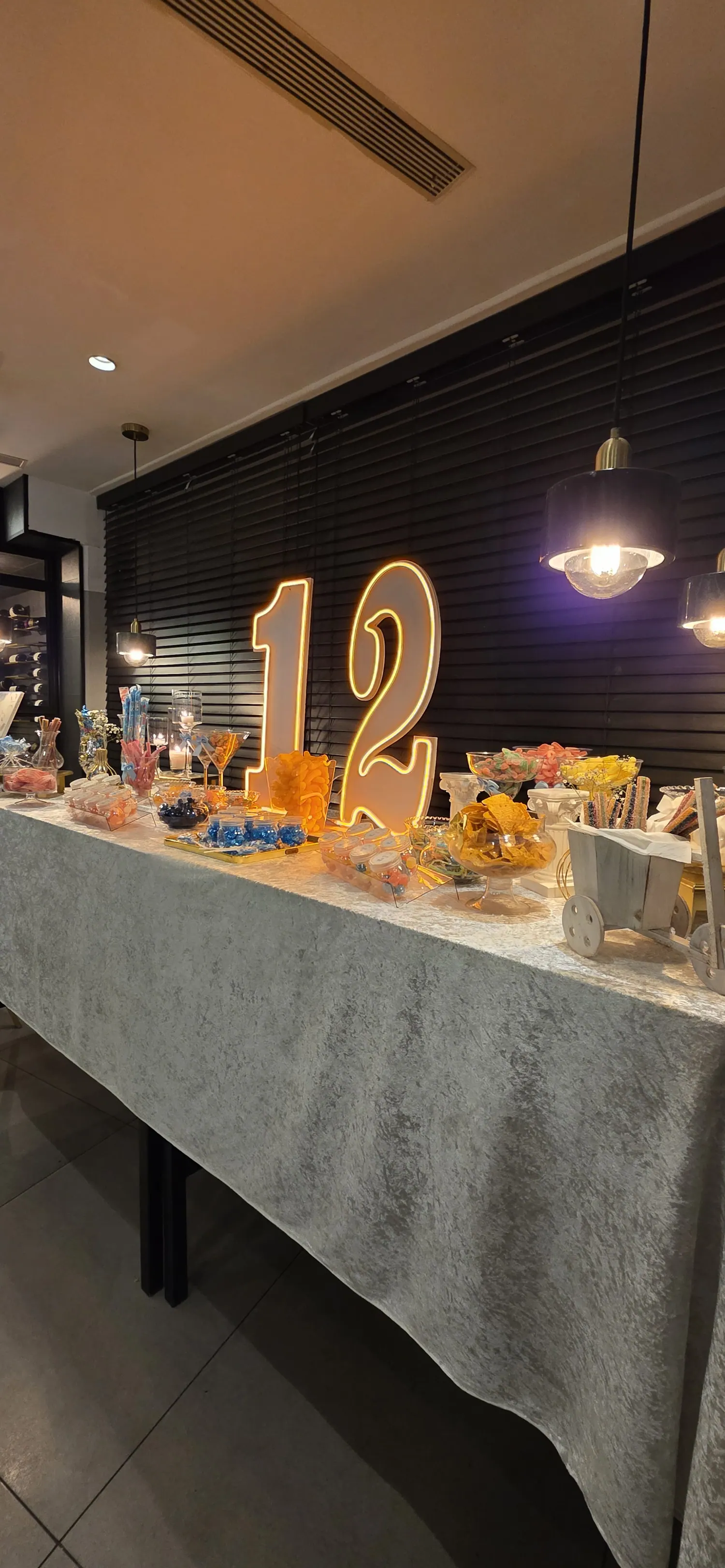 שולחן מתוקים באולם כהה עם מספר 12 מואר בזהב